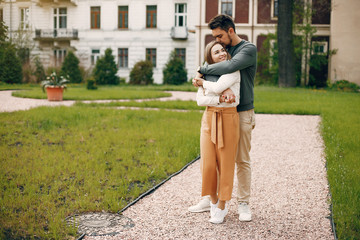 Cute couple in a park. Lady in a white blouse. Guy in a green sweater