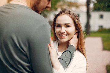 Cute couple in a park. Lady in a white blouse. Guy in a green sweater