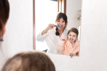 happy family. mother and daughter cleaning teeth together in bathroom.