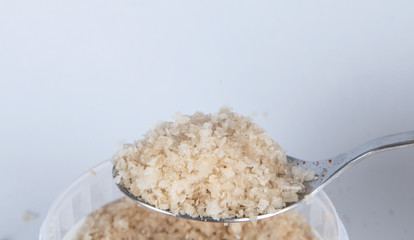 Rock salt on a kitchen spoon on white background