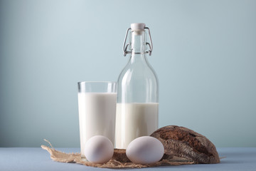 Glass of milk, chicken eggs, on a blue background, side view