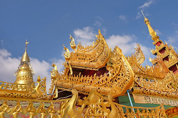 View of the golden roof of a Burmese Pagoda in Mingun, Mandalay, against a blue sky.