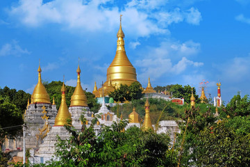 Naklejka premium View of the golden roof of a Burmese Pagoda in Mingun, Mandalay, against a blue sky.