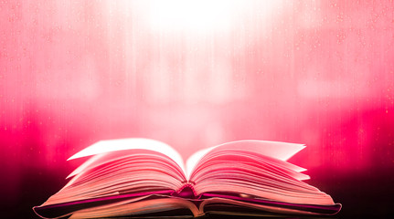 An ancient book that opens with magic, the magic light in the darkness on the wooden table, by the bright light shining down as the power to search for knowledge, religion and background