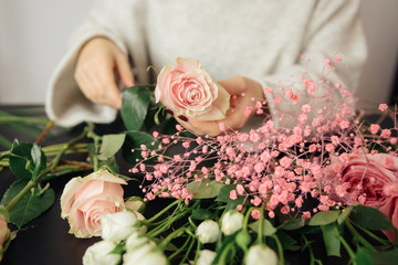 Female florist create a bouquet at workplace. Floristics workshop. Making beautiful flower bouquets and floral decorations.
