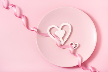 Romantic pink background, plate and hearts with ribbon, Valentine's day celebration, love concept