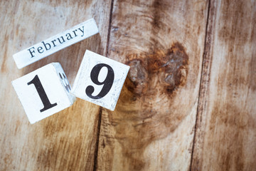 February 19th. Day 19 of February month, white calendar blocks on vintage wooden table background. Winter time. Empty space for text.