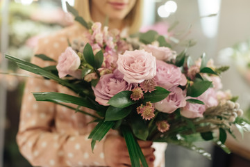 Female professional florist prepares the arrangement of wild flowers. Flower shop. Florist at work