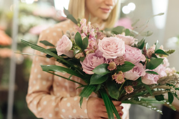 Female professional florist prepares the arrangement of wild flowers. Flower shop. Florist at work