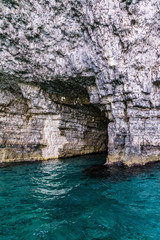 Tunnel in the rock filled with clear blue sea water