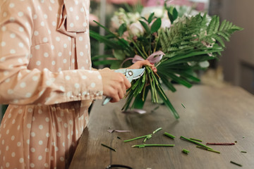 Florist makes a bouquet. Working florist in a flower shop. Woman making fashion modern bouquet of different flowers. Women working with flowers in workshop