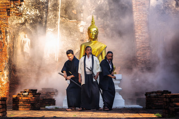 Obraz premium Samurai warrior standing with a sword in front of Buddha.