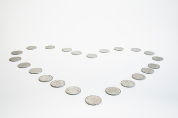 Coins in the shape of a heart for Valentine's Day. Love of money or through money. On a fir-tree background