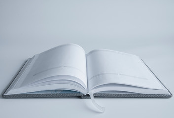 An open book or notebook with blank pages. On a white or gray background