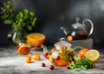 Fruit tea with mint, oranges and cranberry on dark stone background. A cup of hot tea