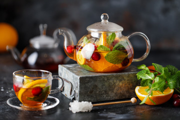 Fruit tea with mint, oranges and cranberry on dark stone background. A cup of hot tea