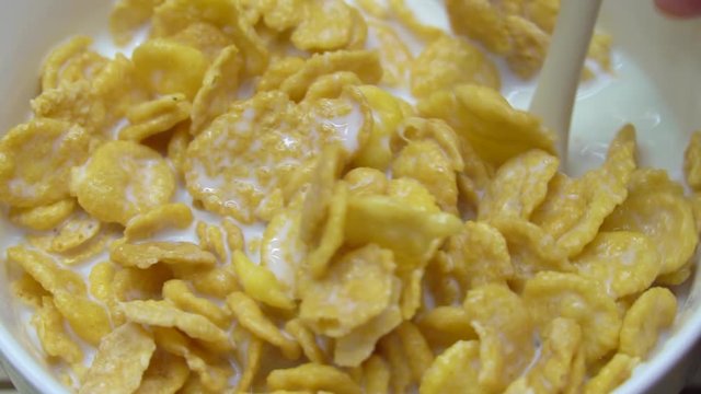 Slow motion footage of pouring milk onto cornflakes in a bowl. healthy conceptual frames.