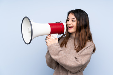 Young brunette woman wearing a sweater over isolated blue background shouting through a megaphone