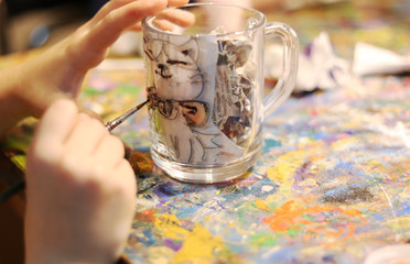 girl paints a glass mug with paints