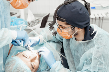 Fototapeta premium Dentists will perform an operation, implant placement. Real operation. Tooth extraction, implants. Professional uniform and equipment of a dentist. Healthcare Equipping a doctor’s workplace. Dentistry