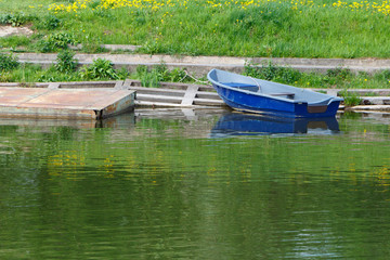 Fototapeta na wymiar Blue dinghy at the shore, near the metal Pantone. Summer sunny day.