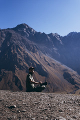 Fototapeta premium stylish bearded man with camera in hands on top of Georgian mountains: nature photographer traveler taking photo of beautiful landscape from top of the mountain