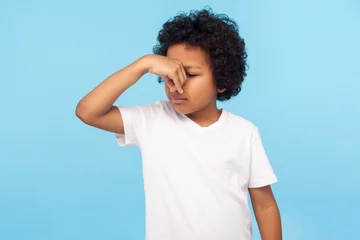 Foto op Canvas Bad smell. Portrait of displeased confused little boy in T-shirt holding breath, pinching his nose, feeling disgust to stink, fart, intolerable odor. indoor studio shot isolated on blue background © khosrork