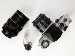 An old analog film photo camera with a roll of film and a telephoto lens