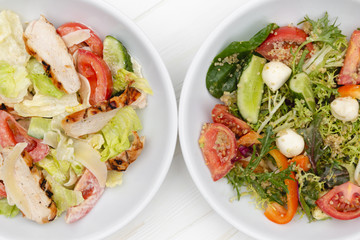 deep plates with fresh salad ingredients mixed with sauce placed on an attractive white table background. A place for a menu, banner or advertisement