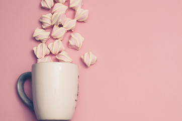 Marshmallows are poured into a cup. Pink color background