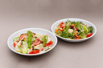white deep plates with fresh salad ingredients mixed with sauce placed on an attractive background. A place for a menu, banner or advertisement