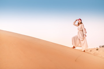 Fototapeta na wymiar Happy asian woman in turban travels in Sahara desert. Adventure and life experience concept