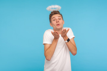 Portrait of angelic lovely handsome man with halo above head sending sensual air kiss to camera,...