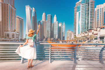 Vrolijk Aziatisch reizigersmeisje dat op een promenade in de wijk Dubai Marina loopt. Reisbestemmingen en toeristische levensstijl in de VAE
