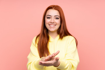 Redhead teenager girl over isolated pink background applauding after presentation in a conference