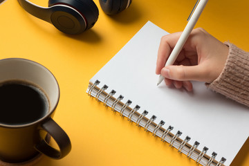 Stock photo of an open notebook page with a hand writing on yellow background