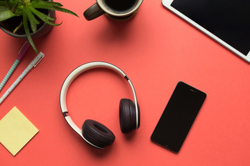 Stock photo of a bluetooth headphones and a smartphone on a red background