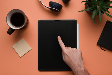 Stock photo of a man hand using a mockup digital tablet on a coral background