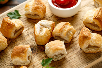 Pork sausage rolls with mustard and ketchup sauce on wooden board