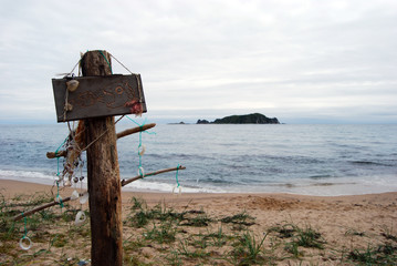 Funny wooden sign with fishes on a sandy beach. Beautiful seascape. Lonely island on the horizon.
