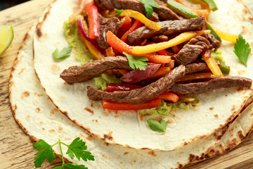Beef Steak Fajitas with mix pepper, onion and avocado on wooden board