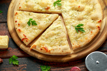 Garlic cheese pizza on wooden board with herbs.