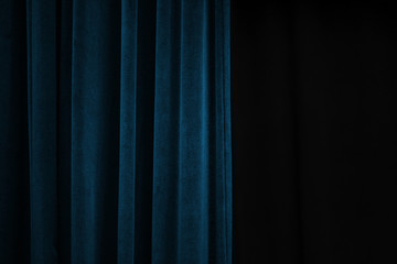Dark blue velvet curtain on one side of a black theatre stage, event background concept with large...