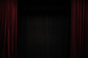 Very dark red velvet curtain on the sides of a black theatre stage, background frame with large...