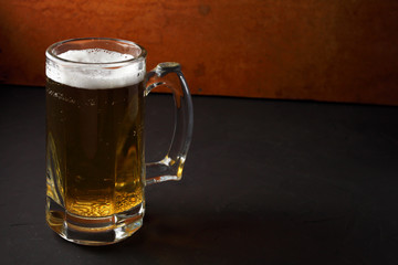 a glass of beer stands on a dark table