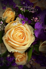 Close-up of a beautiful spring bouquet with pale cream roses and purple orchids. Decorative composition of a greeting card for a birthday holiday. Copy space.