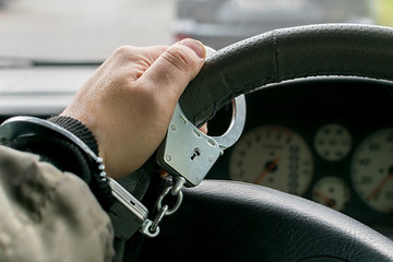 car driver's hand handcuffed to steering wheel, arrest, driving ban by traffic violator