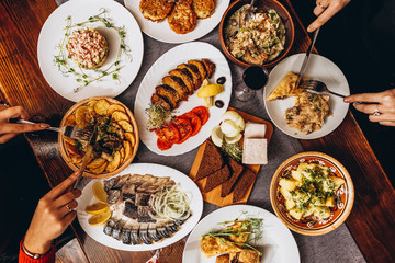 large wooden table with mouthwatering national Russian dishes. The restaurant where the food is cooked is as satisfying and delicious as home, top view