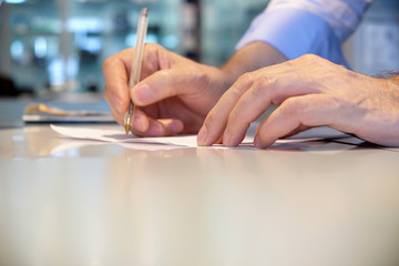 Mani di un uomo d'affari scrivono  su un foglio di carta