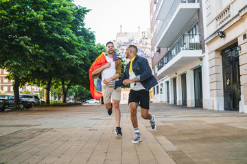 Gay couple holding their hands and running together.